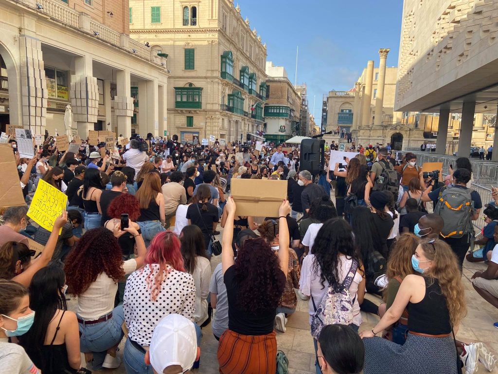 Demonstrators take a knee for a minute of silence in memory of Lassana Cisse