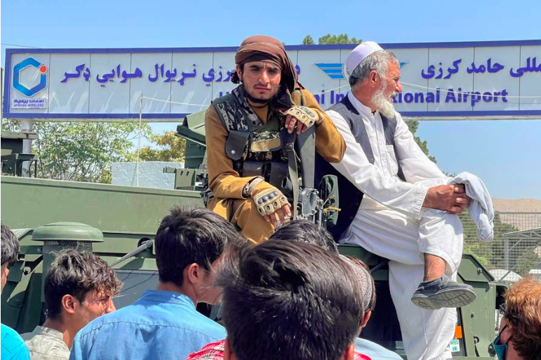 A member of Taliban forces sits on an armored vehicle outside Hamid Karzai International Airport in Kabul